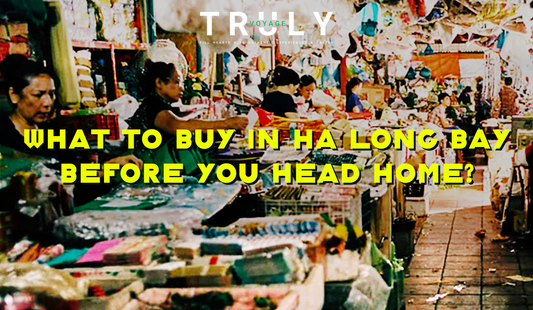 Truly Voyage blog post graphic titled "What to Buy in Ha Long Bay Before You Head Home?" featuring local vendors selling traditional crafts, gifts, and souvenirs at a bustling indoor market.