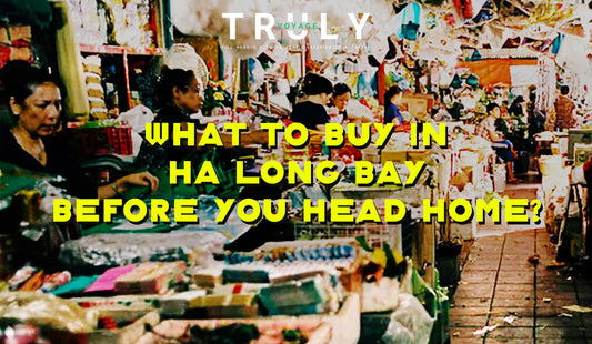 Truly Voyage blog post graphic titled "What to Buy in Ha Long Bay Before You Head Home?" featuring local vendors selling traditional crafts, gifts, and souvenirs at a bustling indoor market.